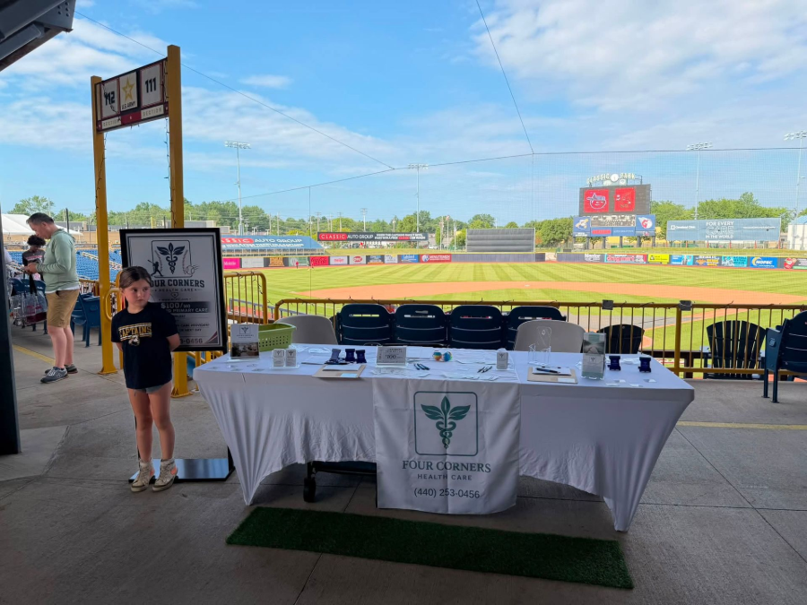 Concession table at a baseball stadium, with a child standing beside it and the field in the background