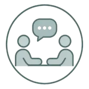 Two people talking at a table with a speech bubble icon above them inside a circle