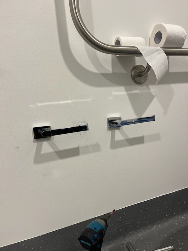 Partially unfinished bathroom wall with two toilet paper holder brackets and a roll on the floor — Rolling With Netherpoel in Bowen, QLD