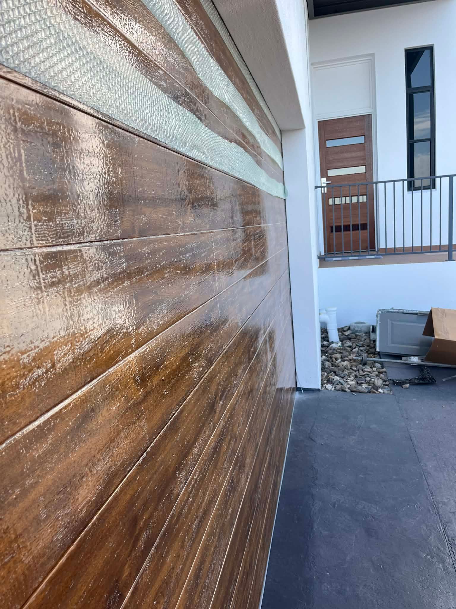 Wooden garage door beside a modern house entrance with a small landscaped walkway — Rolling With Netherpoel in Hamilton Island, QLD