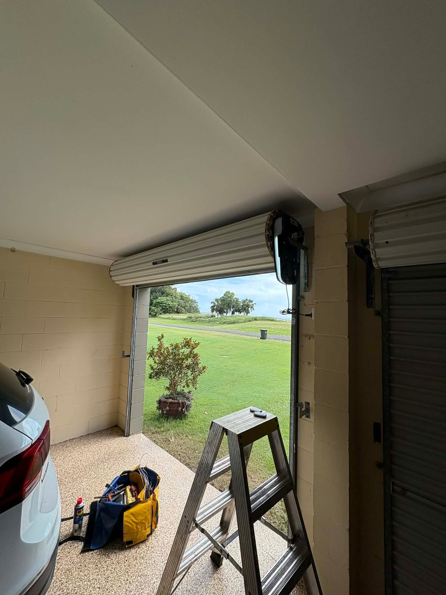 Garage opening to a green yard, with a silver car, step ladder, and tools in the foreground — Rolling With Netherpoel in Hamilton Island, QLD