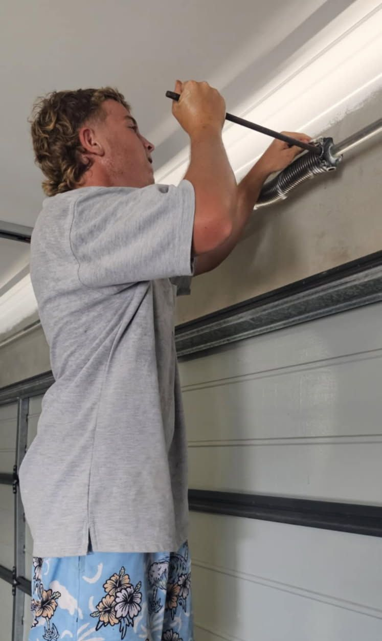 Person using a tool to work on a garage door track overhead — Rolling With Netherpoel in Bowen, QLD