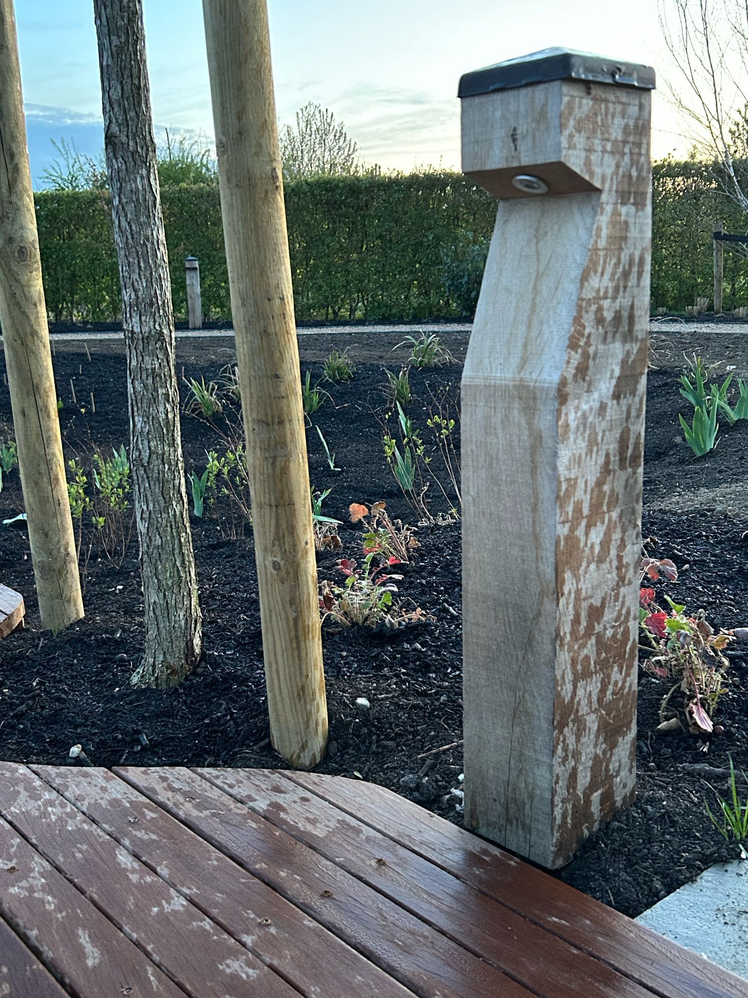 Stenen waterfontein in een tuin met bamboebomen. Donkerhouten terras op de voorgrond.