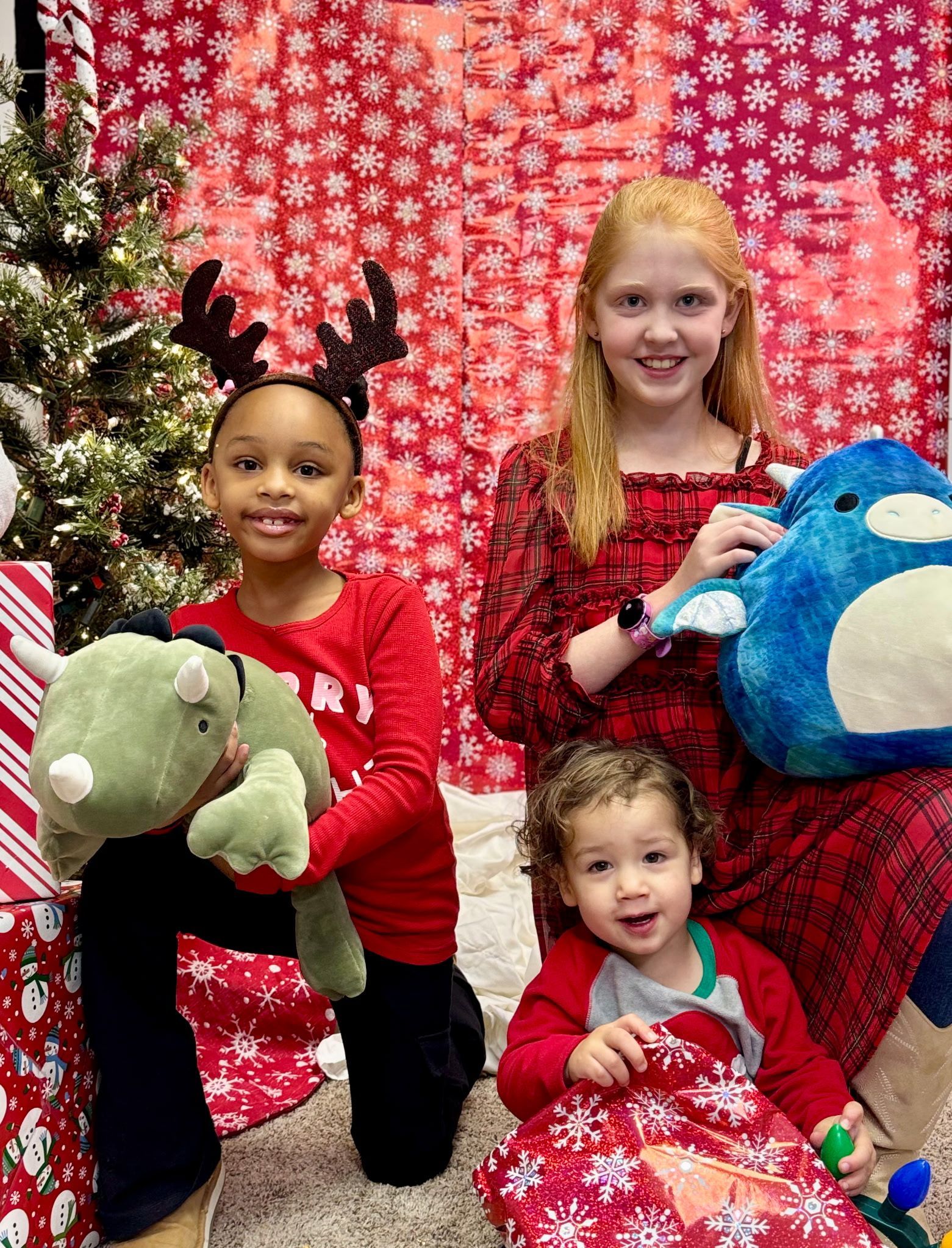 A group of children are posing for a picture in front of a christmas tree.