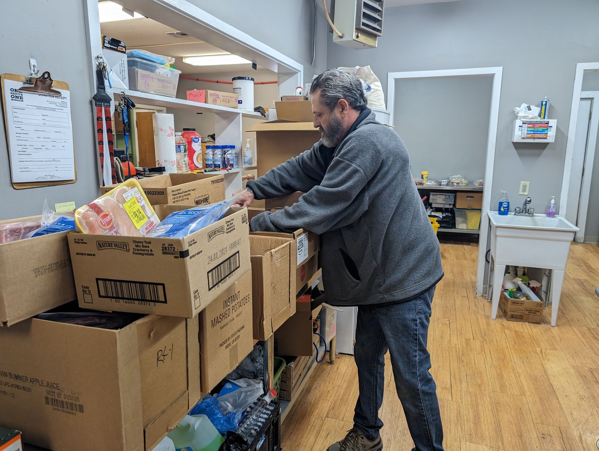 A man is standing in front of a shelf full of boxes.