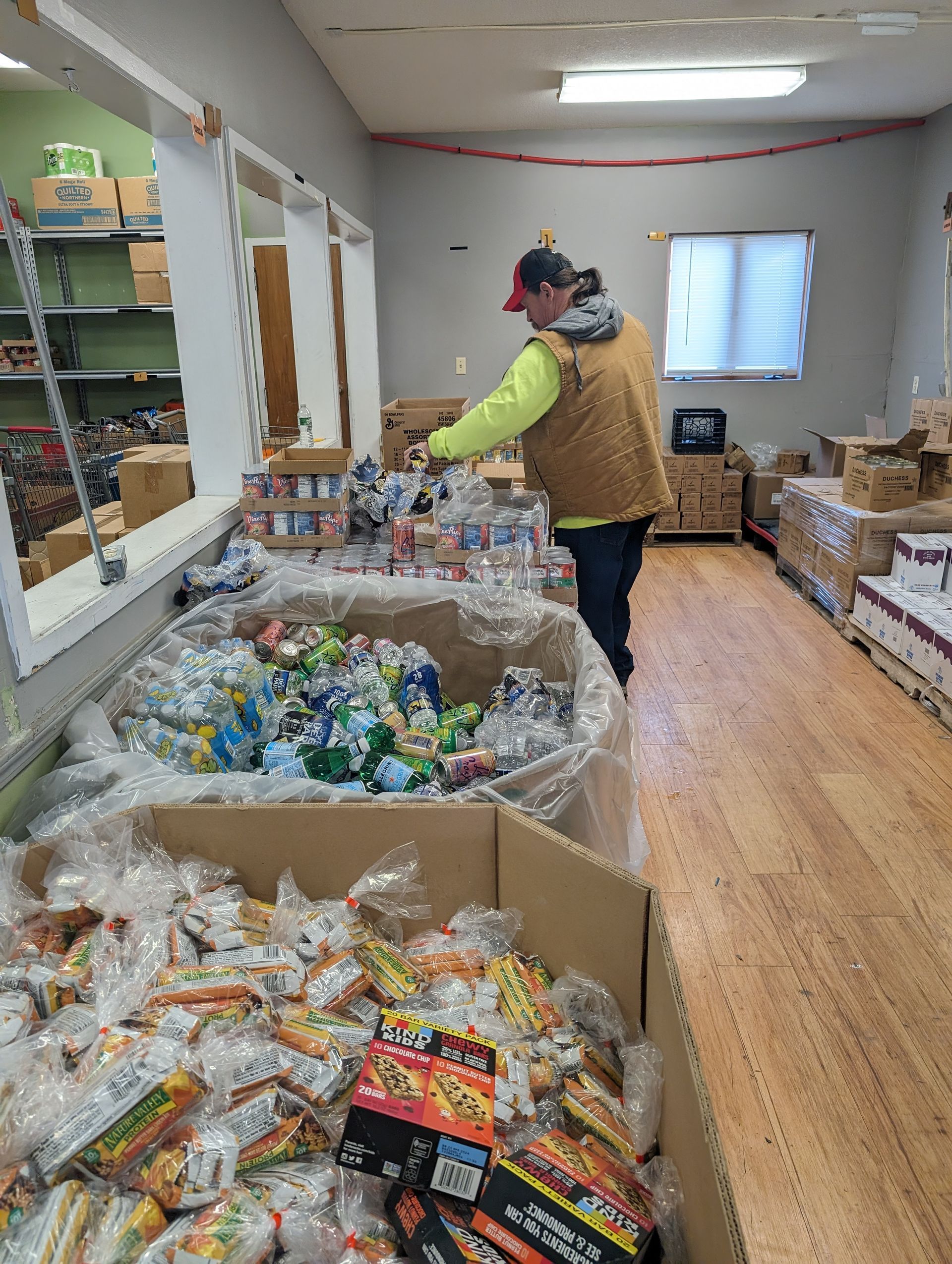 A man is standing in a room filled with boxes of food.
