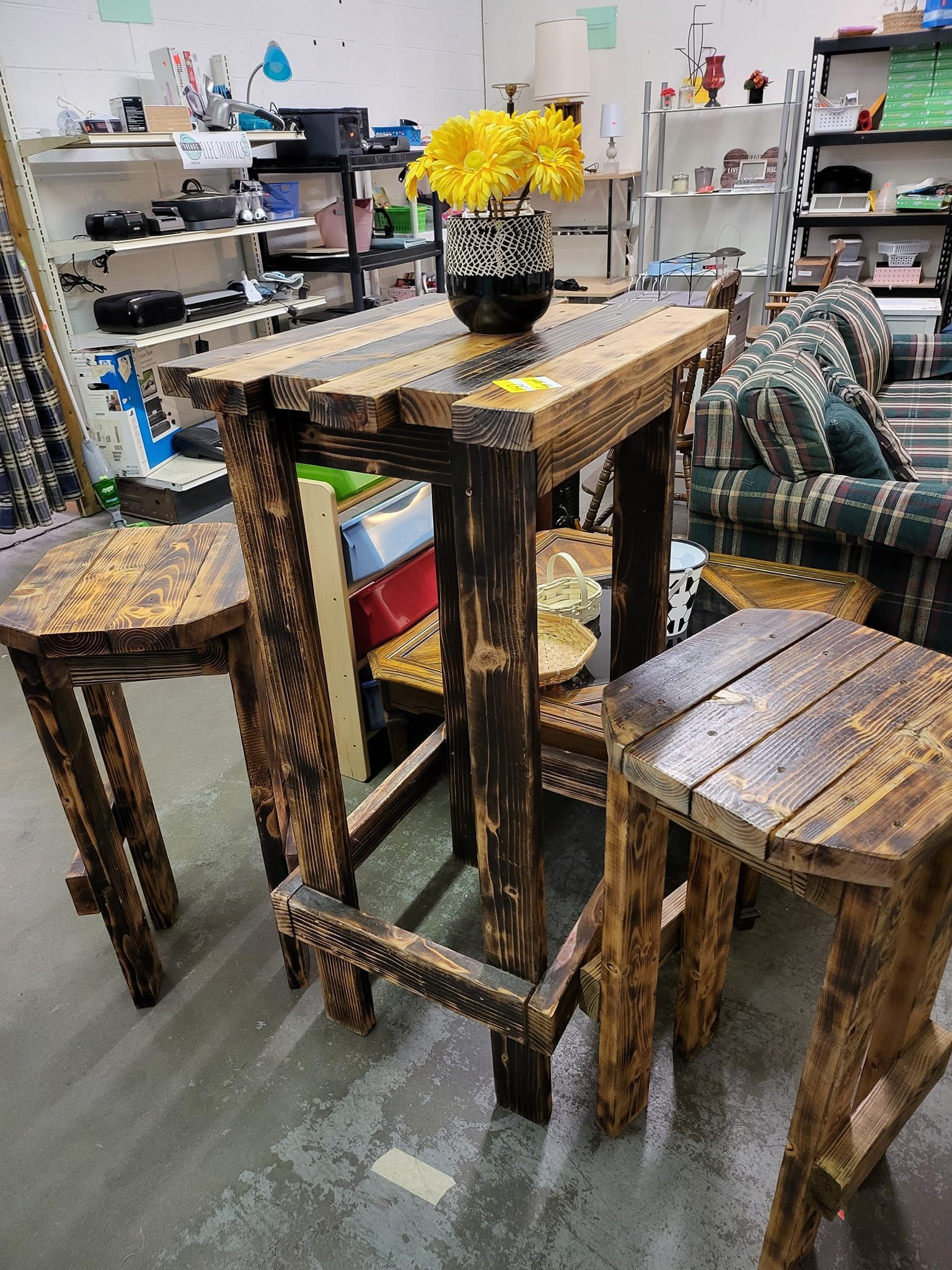 A wooden table and stools in a room with a vase of flowers on it.