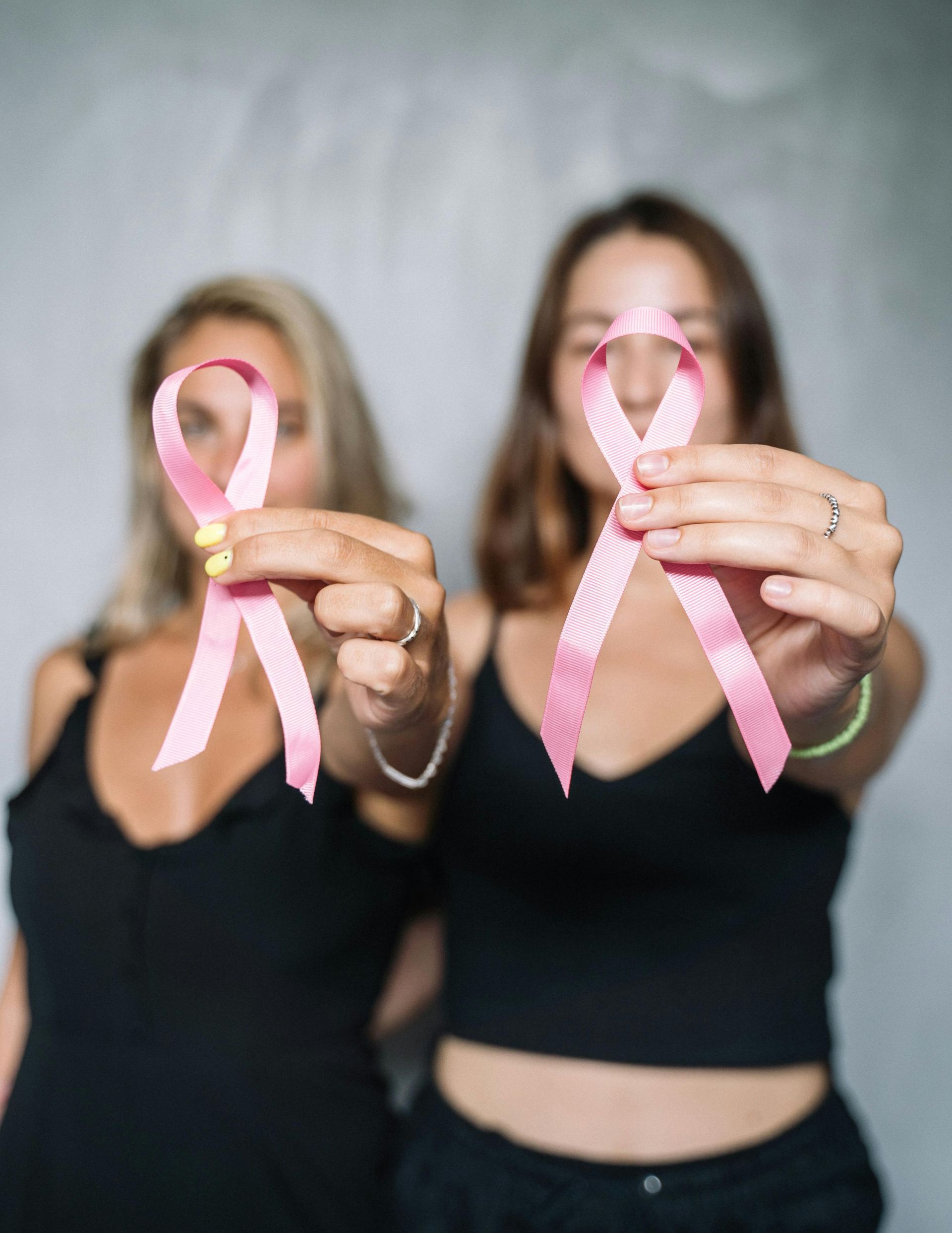 Two women holding pink breast cancer awareness ribbons.