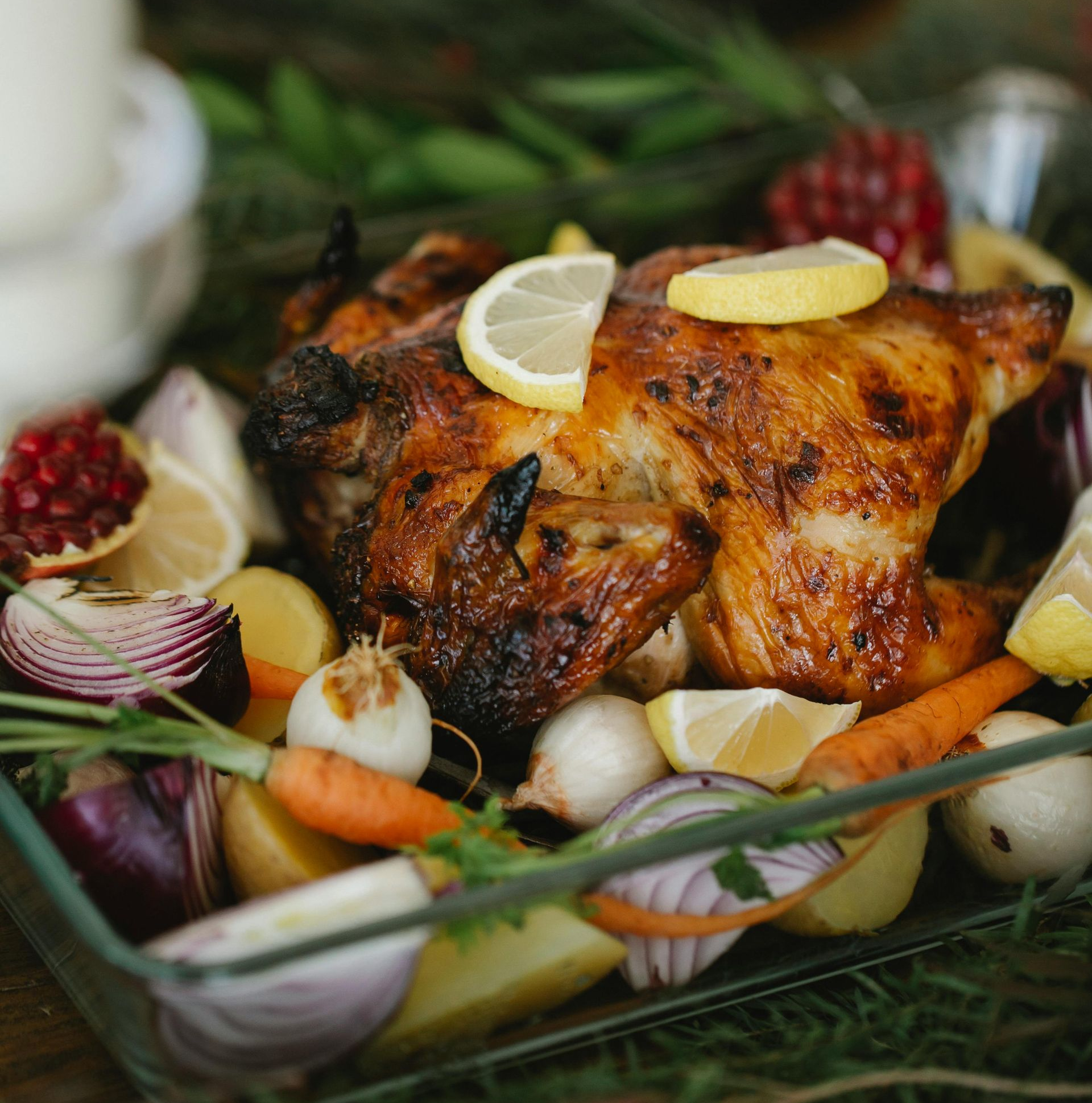 Roasted chicken with vegetables and lemon slices in a glass dish.