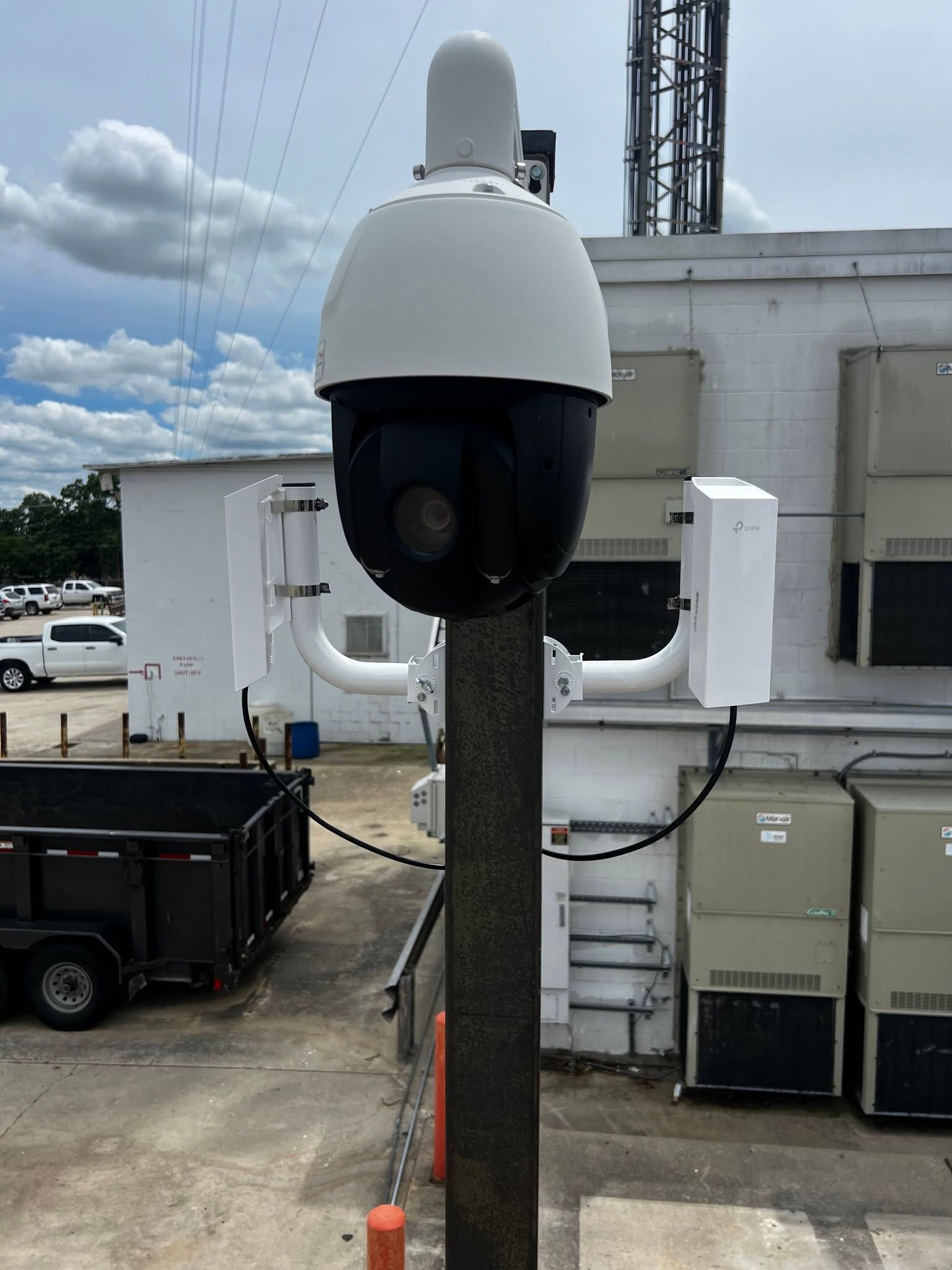 White security camera mounted on a pole outside a building under a cloudy sky