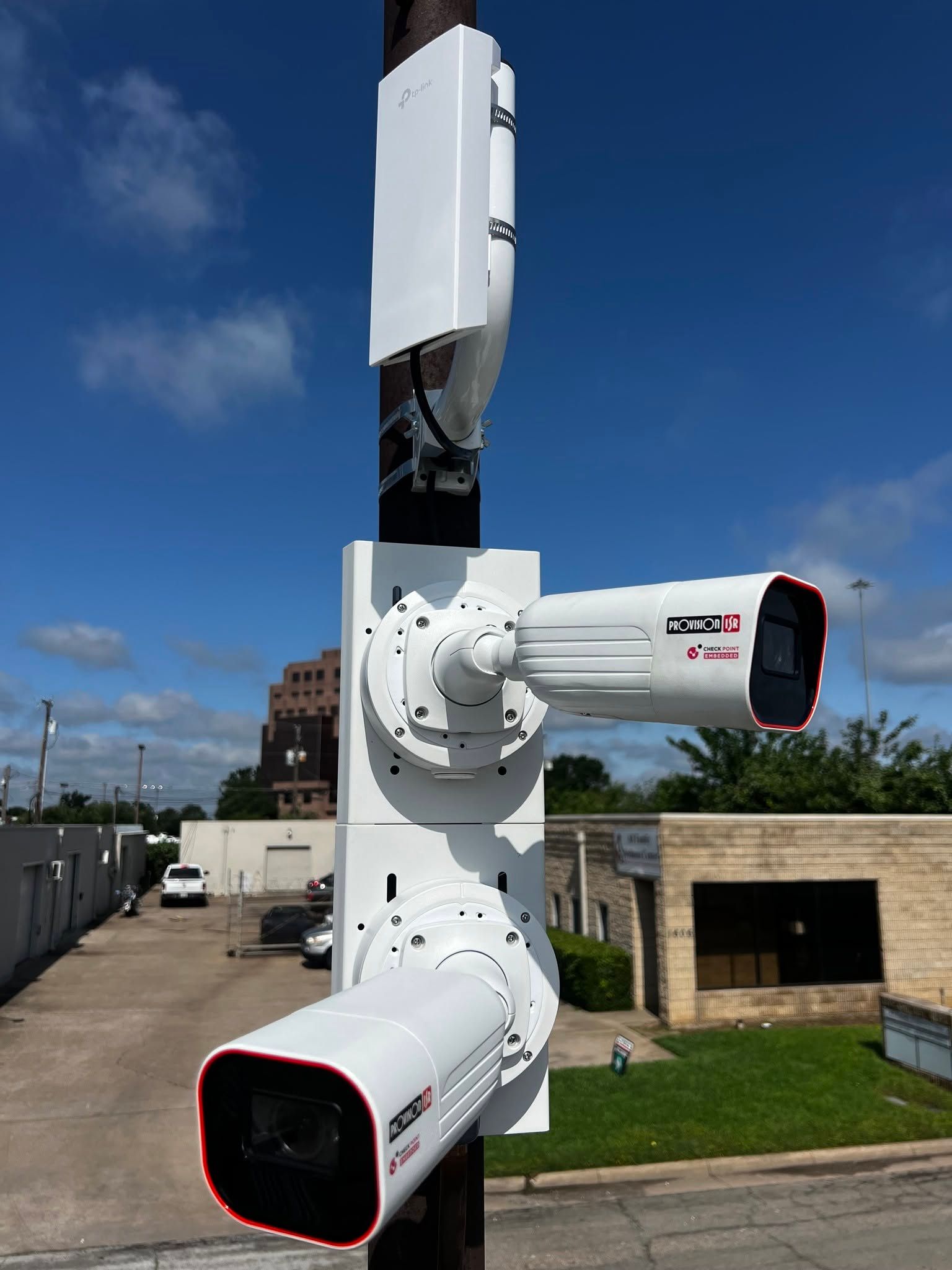 White rooftop cellular antenna with three directional panels against a blue sky.