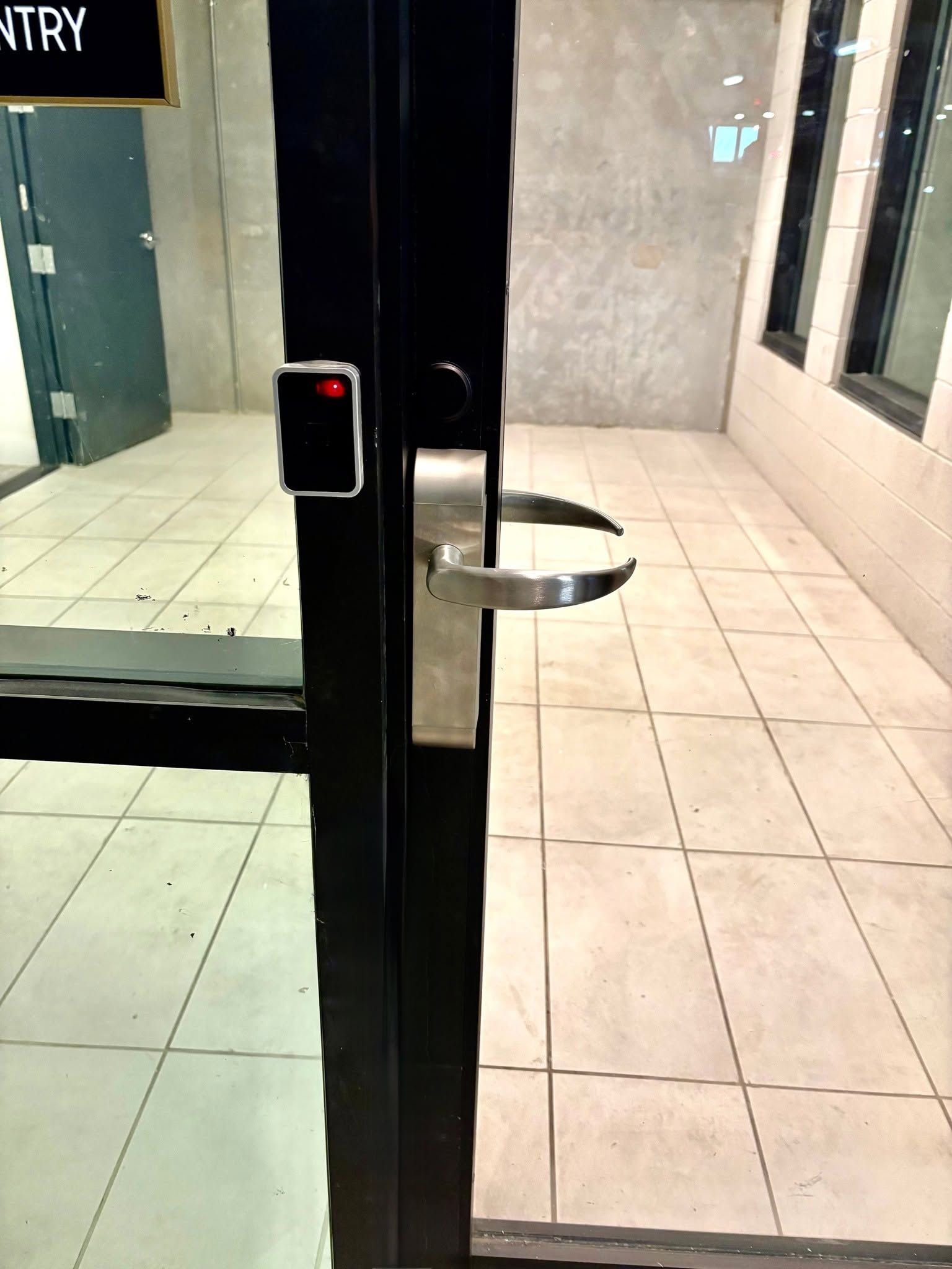 Glass entrance door with metal handle opening to a tiled hallway