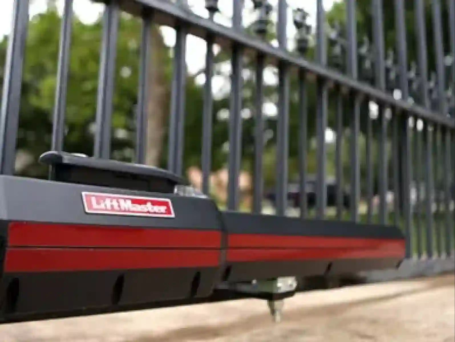 Black and red LiftMaster gate opener mounted on a metal fence outdoors