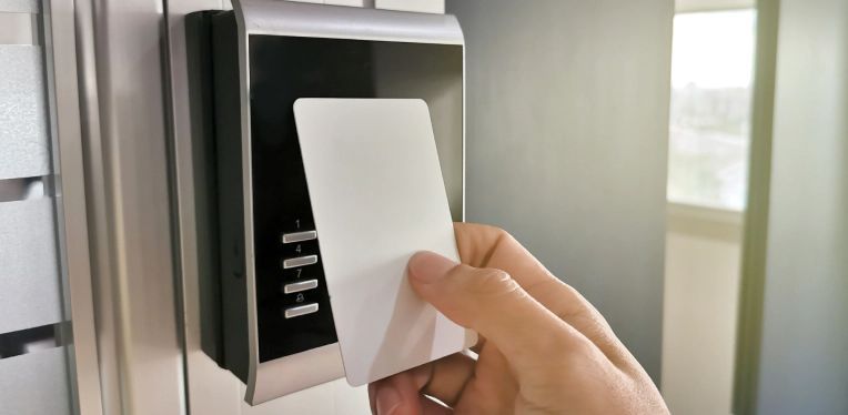 Hand inserting a card into a wall-mounted access control keypad with a fingerprint scanner