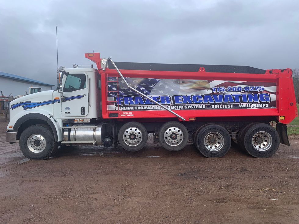 a dump truck is parked in a dirt lot .