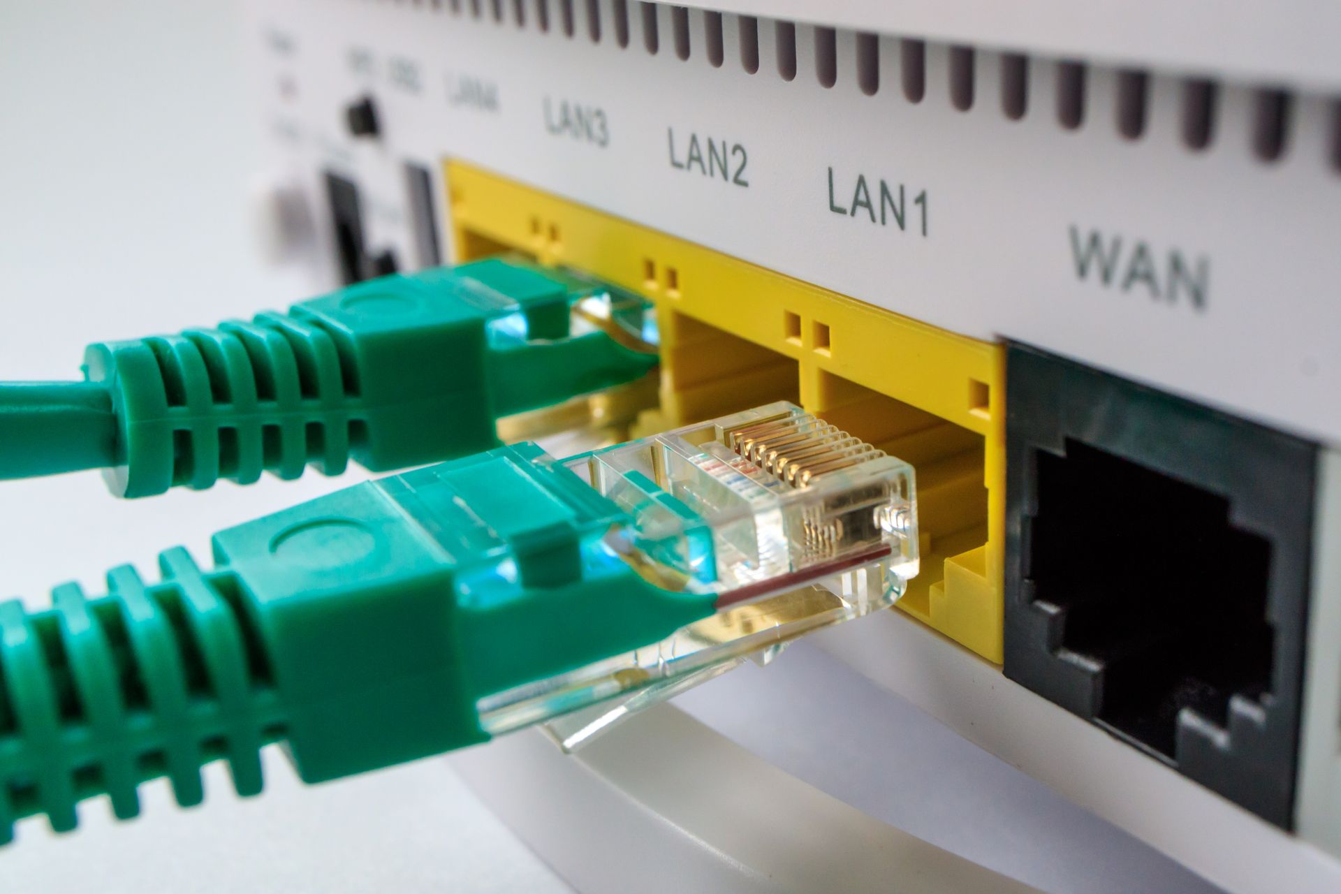 Two green ethernet cables are plugged into a router