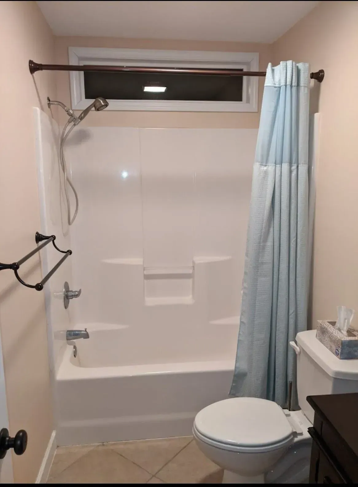 a bathroom with a toilet, tub, shower and window