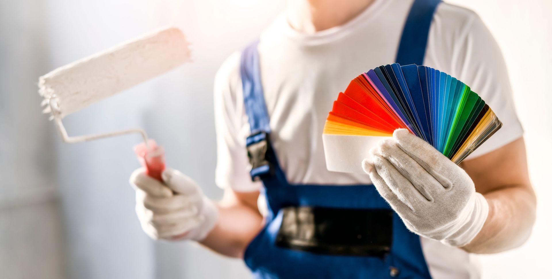 a man is holding a paint roller and a color palette