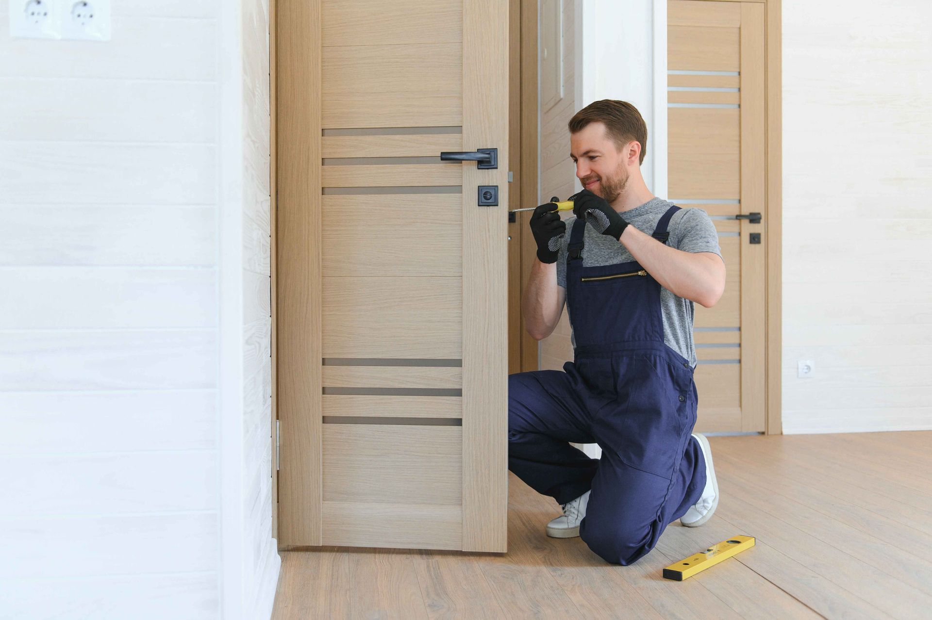 a man is kneeling down and fixing a door with a drill