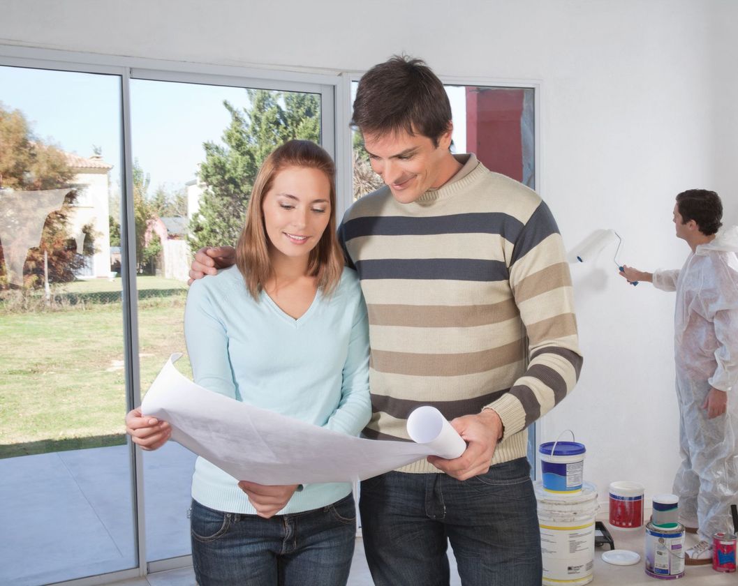 a man and a woman are looking at a blueprint in a room