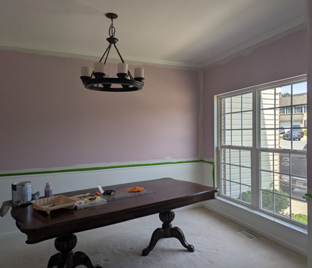 Bright dining room with a dark wooden table, mauve walls, and large windows letting in daylight
