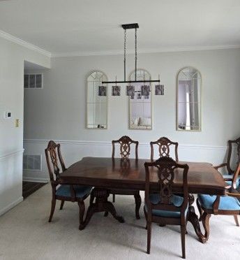 Dining room with dark wood table, ornate chairs, and a hanging light beneath arched wall mirrors