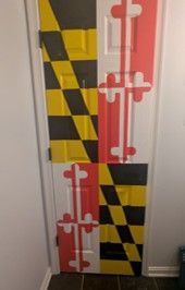 Maryland flag design on a narrow door, with yellow-black checkerboard and red-white cross panels.