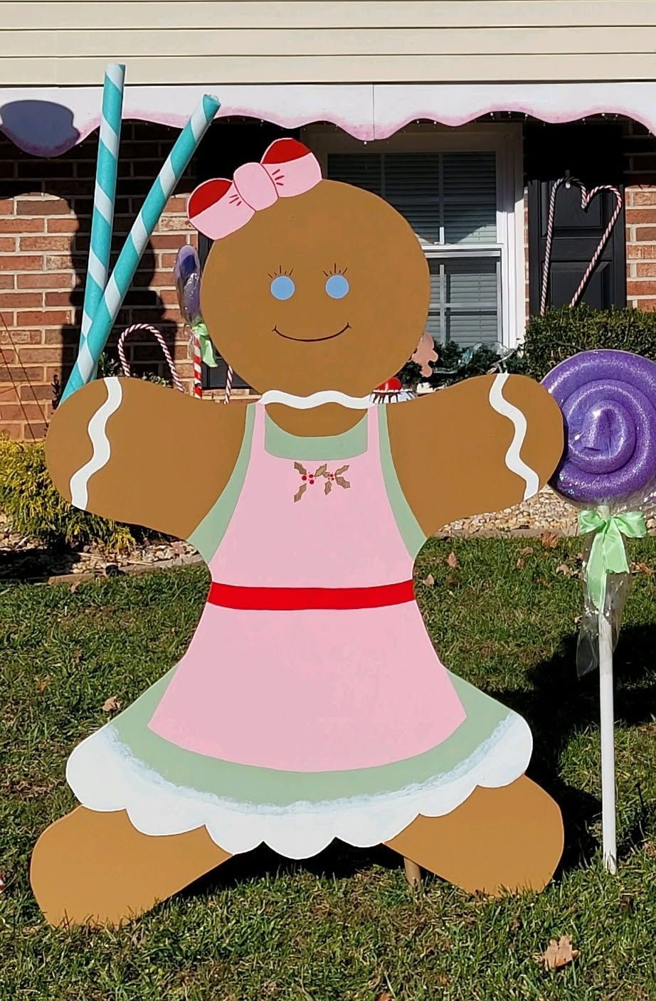 Gingerbread house decoration with pink dress and candy cane accents on a lawn