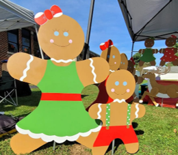 Gingerbread cutout figures outdoors with a green dress, red accents, and candy decorations