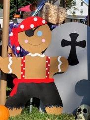 Gingerbread pirate decoration with red hat, black shorts, and a tombstone backdrop in a yard