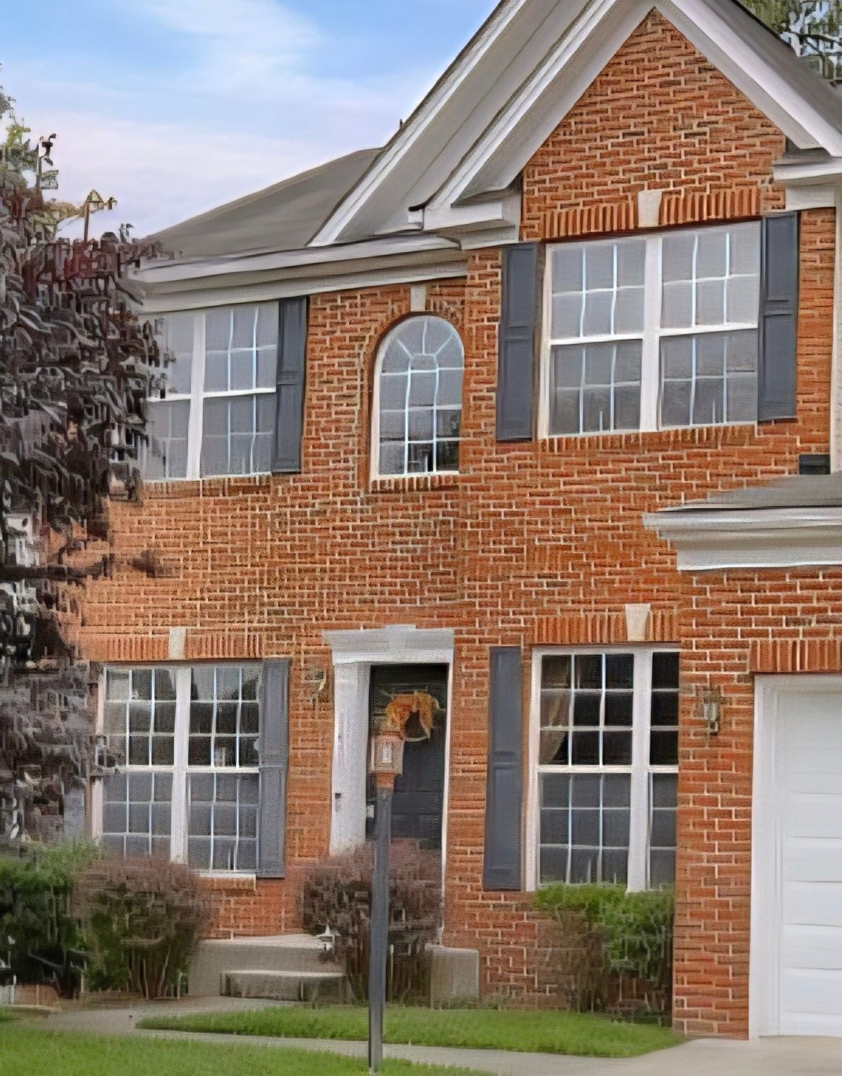 Two-story red brick house with white trim, front windows, and a garage on a quiet suburban street