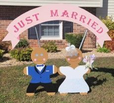 “Just Married” yard display with bride and groom cutouts under a pink arch