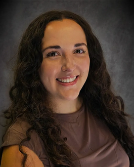 Smiling woman with long dark curly hair in a brown top against a dark studio background