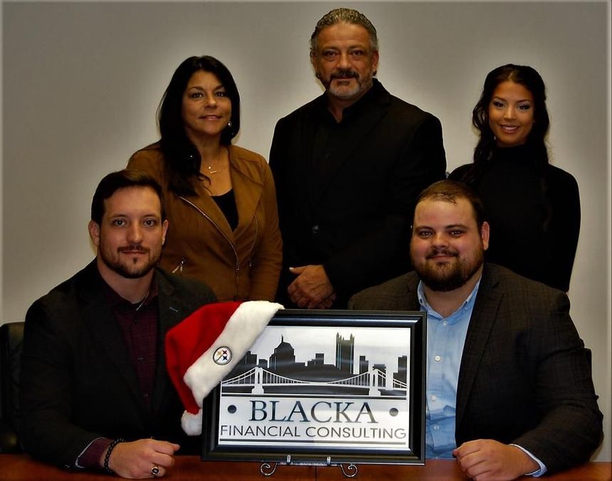 Five people posing behind a Blacka Financial Consulting sign, one wearing a Santa hat
