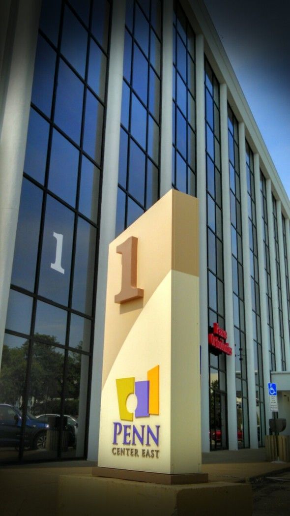 Penn Center East building entrance with large beige pillar and blue glass facade
