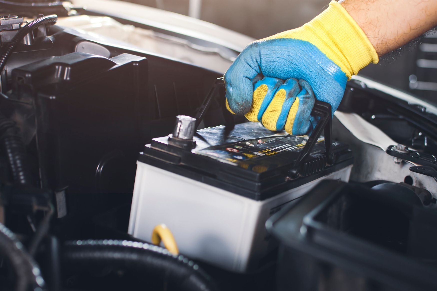A Person Is Working On A Car Battery In A Garage — Cairns Roadside Assist In Manunda, QLD