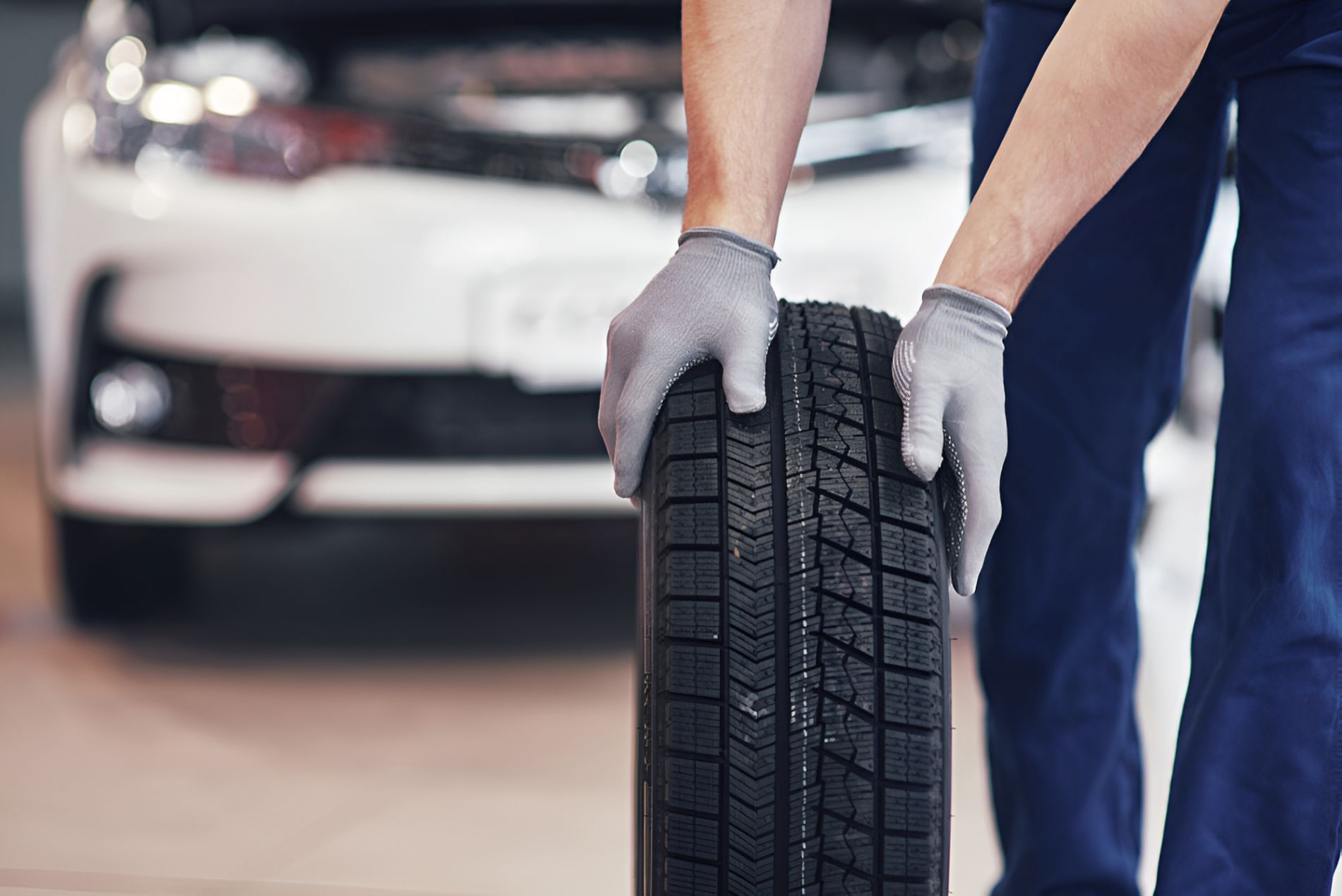 A Man Is Holding A Tire In Front Of A Car — Cairns Roadside Assist In Kuranda, QLD