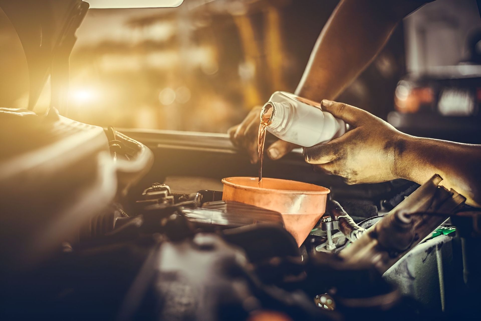 A Man Is Pouring Oil Into A Car Engine — Cairns Roadside Assist In Mareeba, QLD