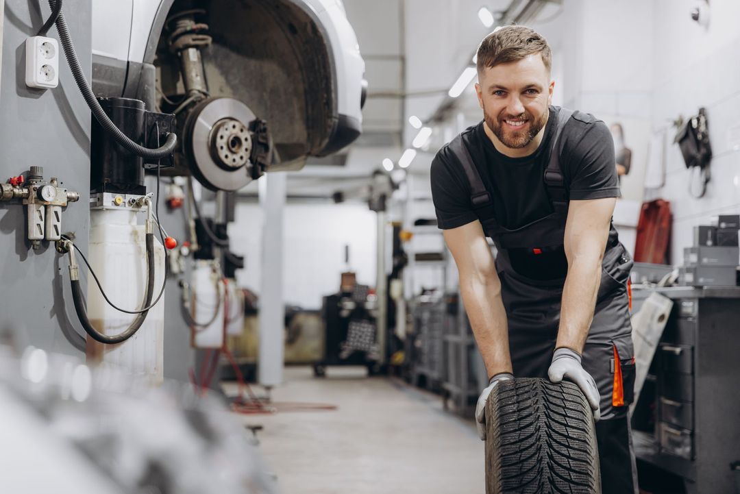 Mechanic smiling and holding a tire in an auto repair shop