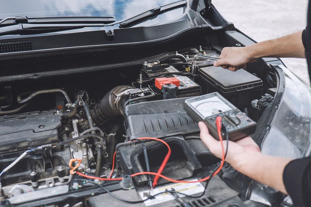 Person using a multimeter to test a car battery in an open engine bay