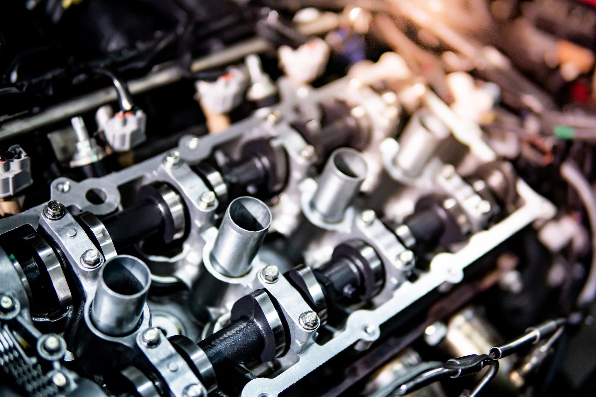 Close-up of shiny metal engine parts with bolts and hoses in a workshop setting