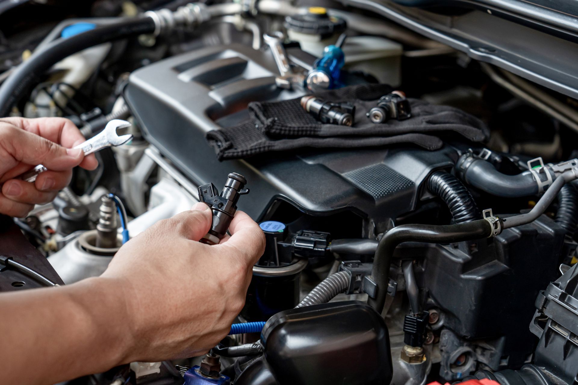 Mechanic hands installing a car engine sensor in an open hood bay