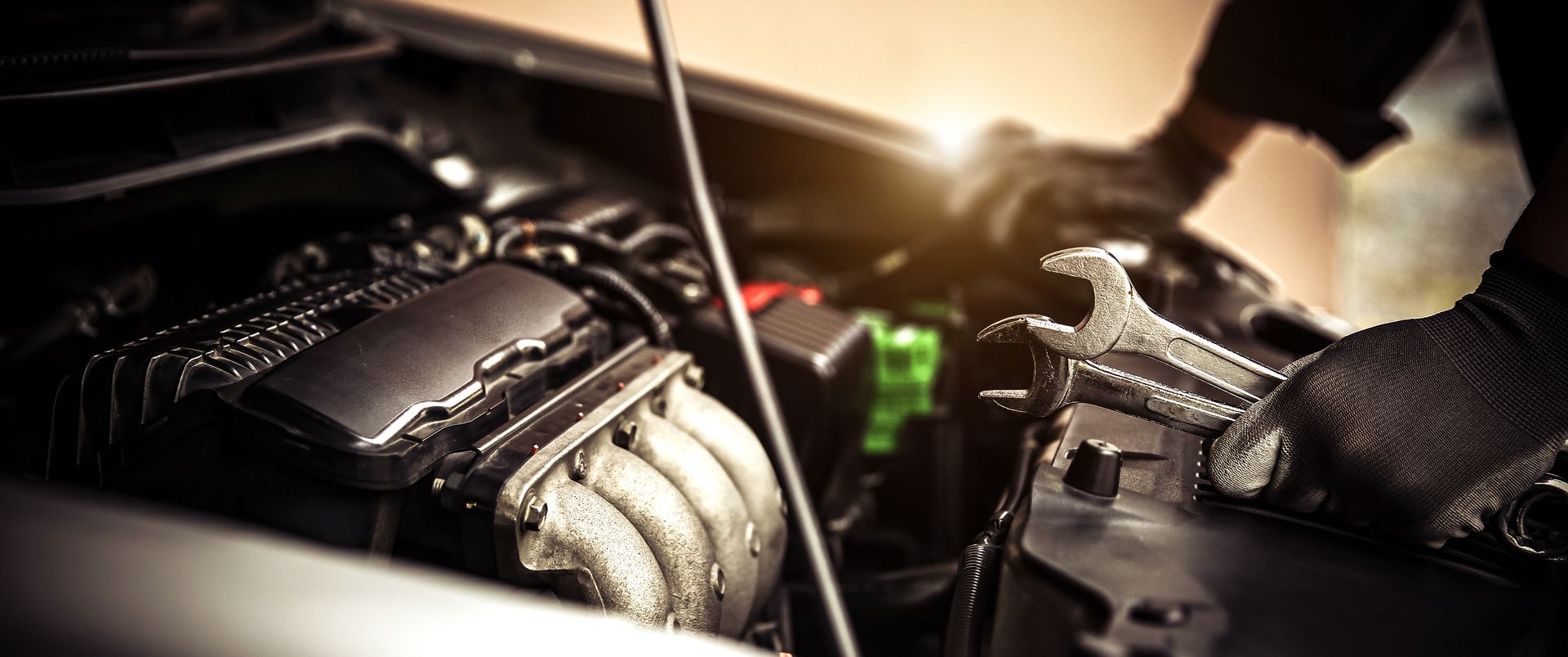 Mechanic’s gloved hands working on a car engine in a dimly lit garage