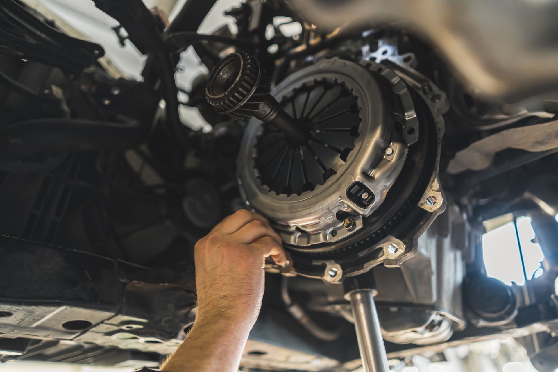 Mechanic installing a clutch assembly under a car on a lift Mechanic installing a clutch assembly under a car on a lift