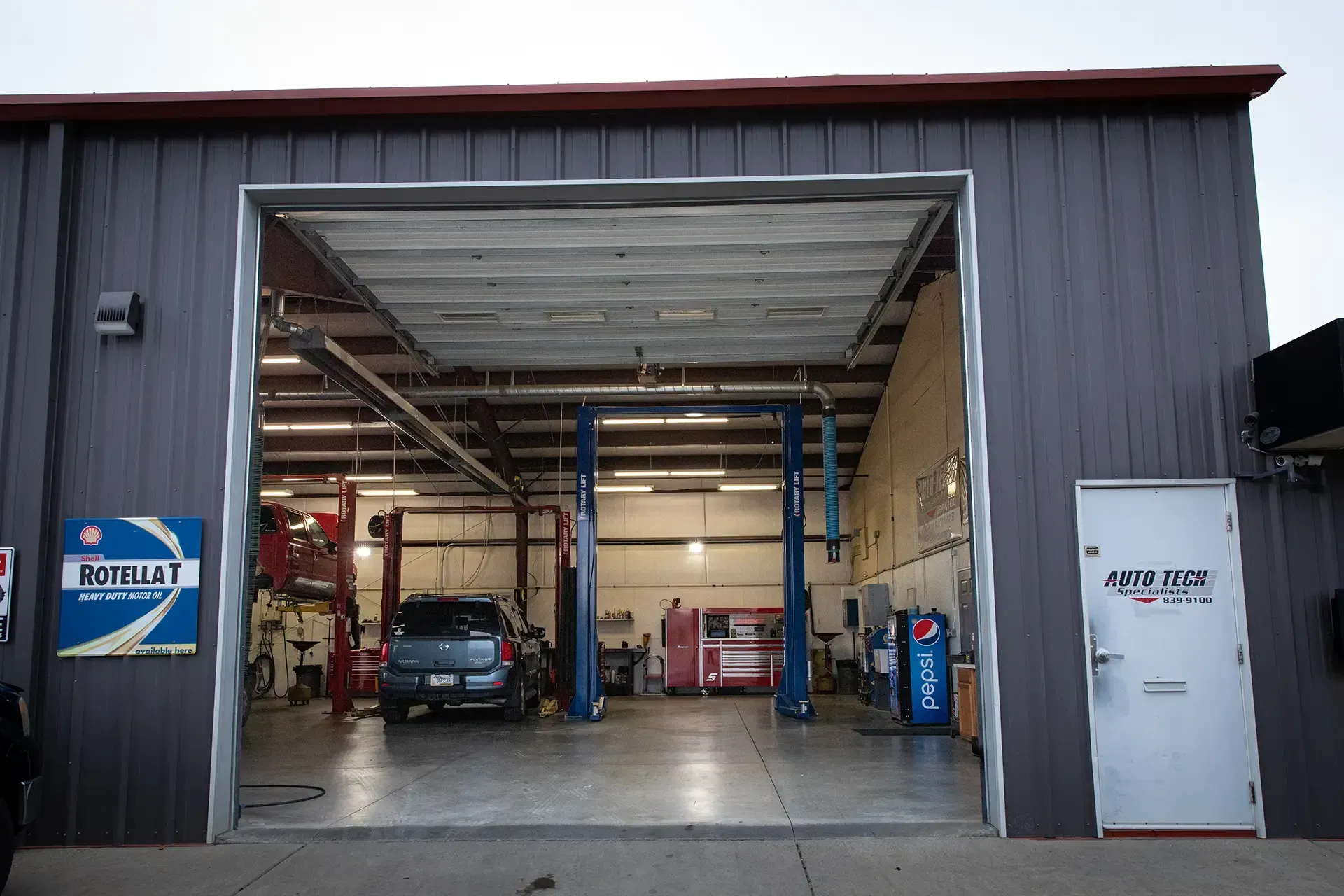Open auto repair garage with cars inside and an open bay door