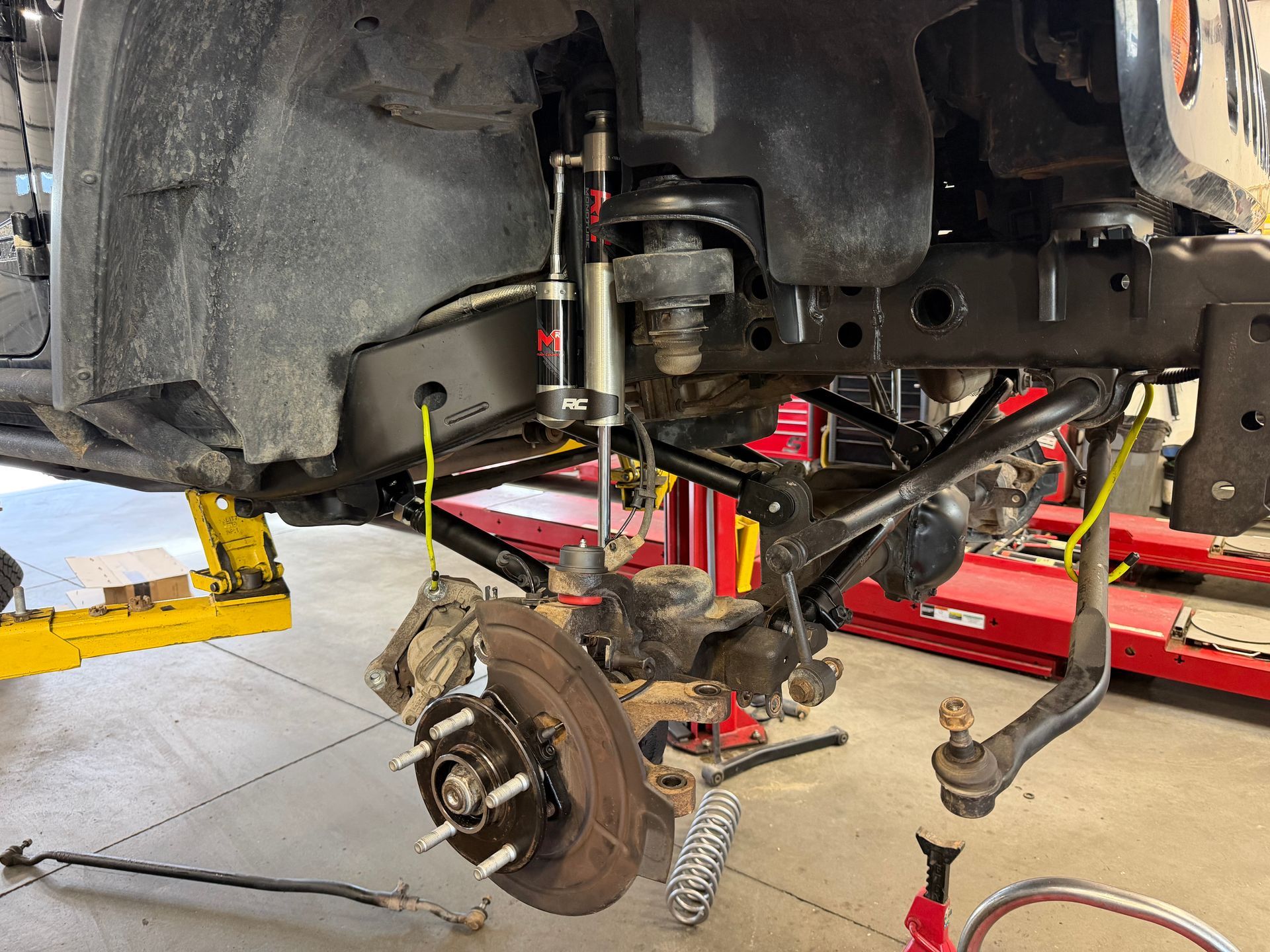 Mechanic working on a car brake assembly in a garage, lit by warm light