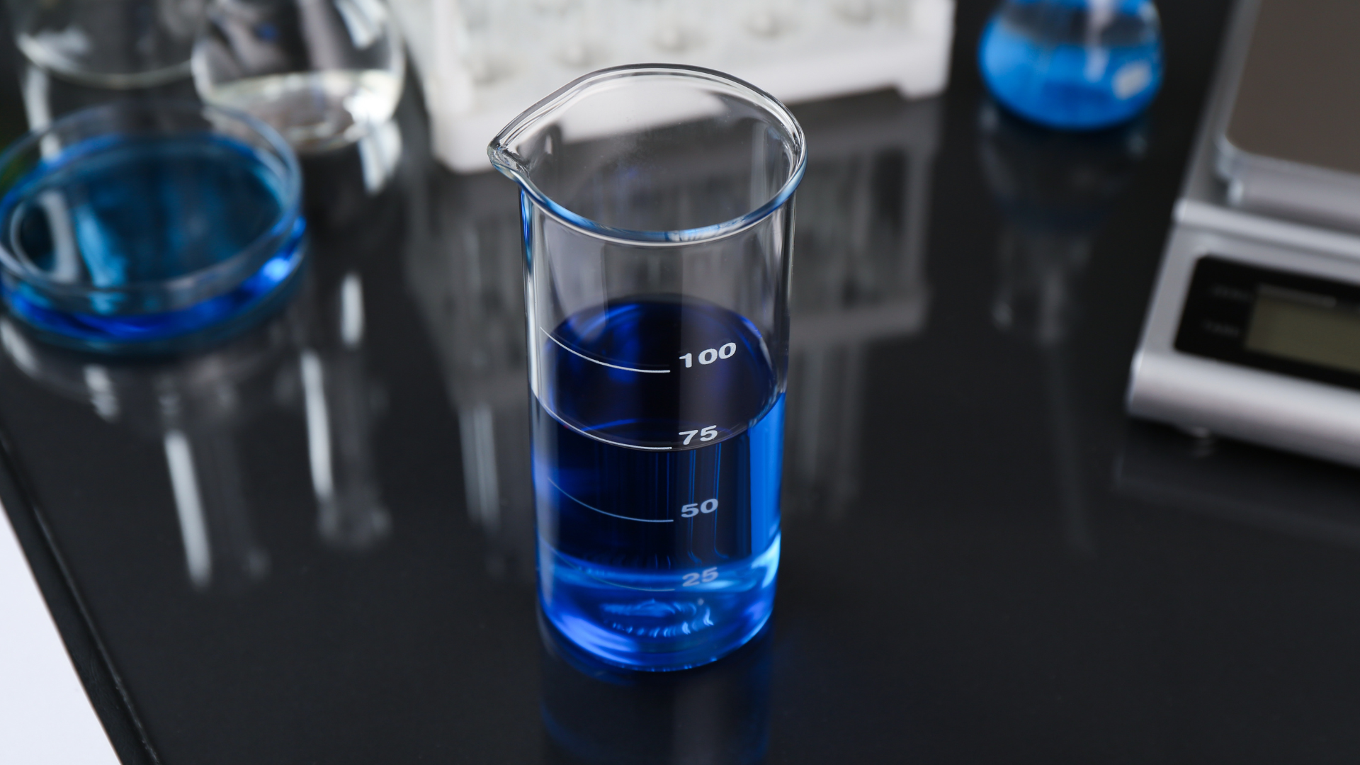Blue liquid in a beaker on a lab bench with other glassware in the background