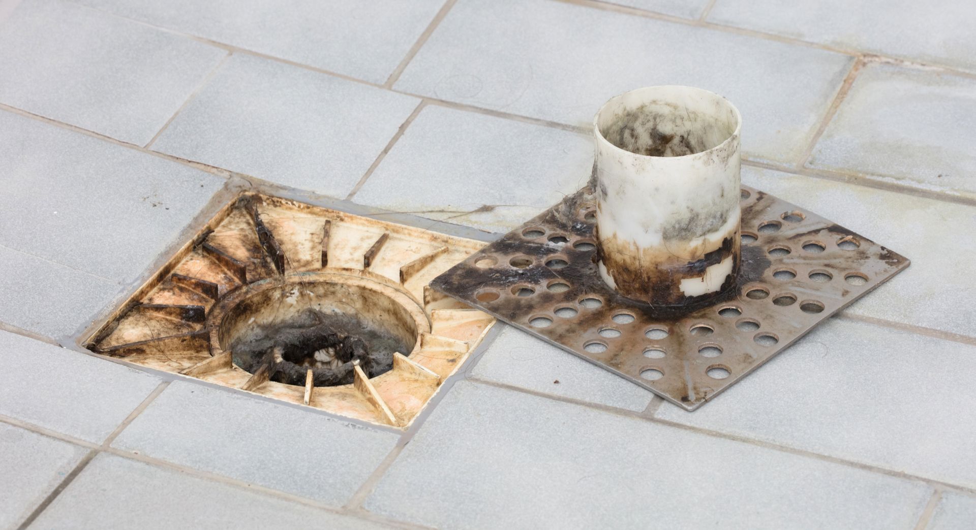 Damaged sidewalk with two open manholes and a rusty pipe protruding from one cover