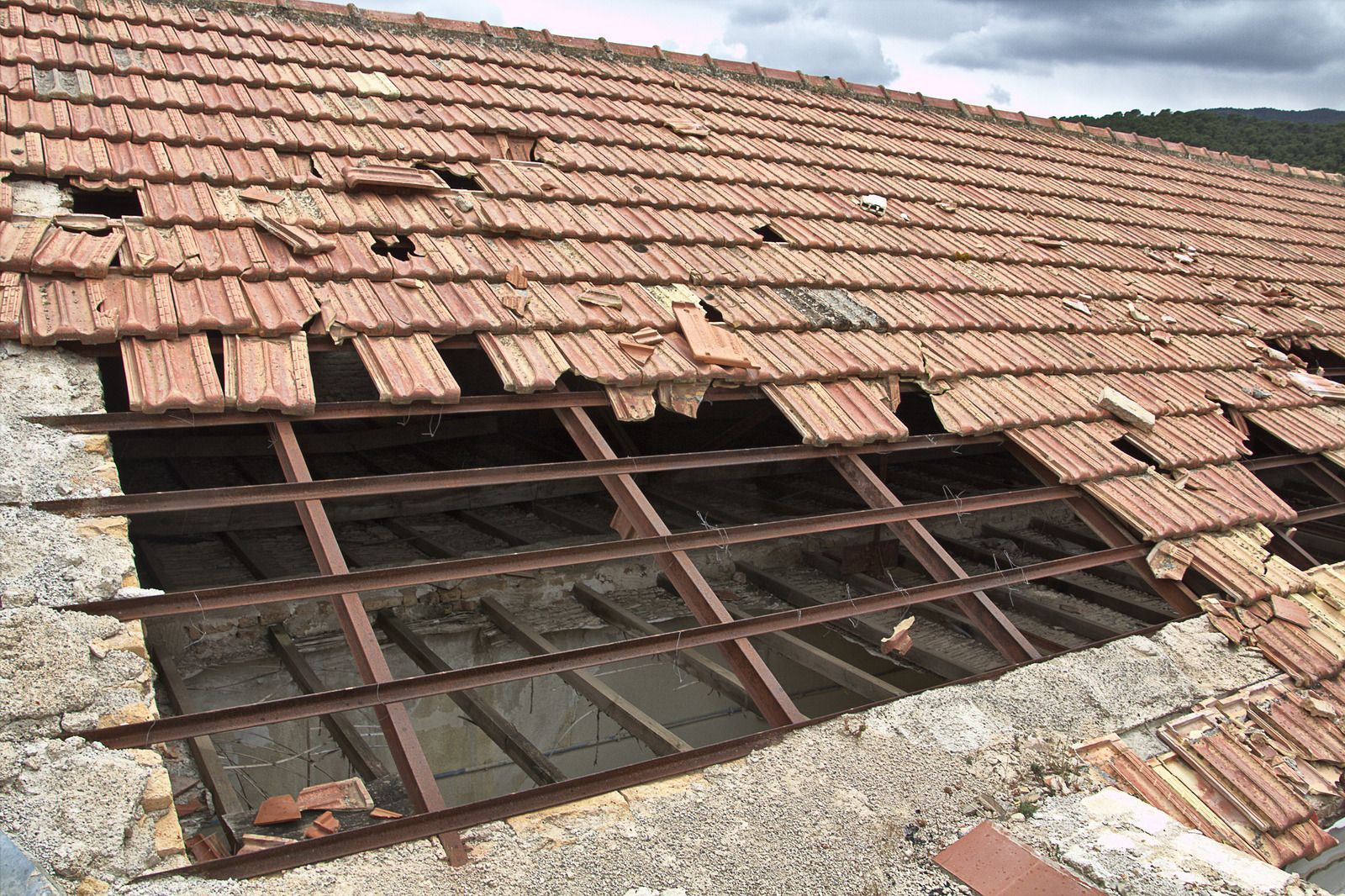 A roof with a lot of broken tiles and a metal frame.