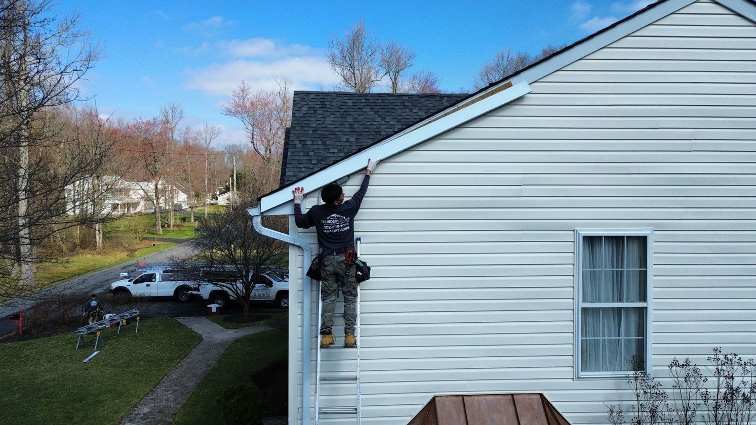 Two men are working on the roof of a house.